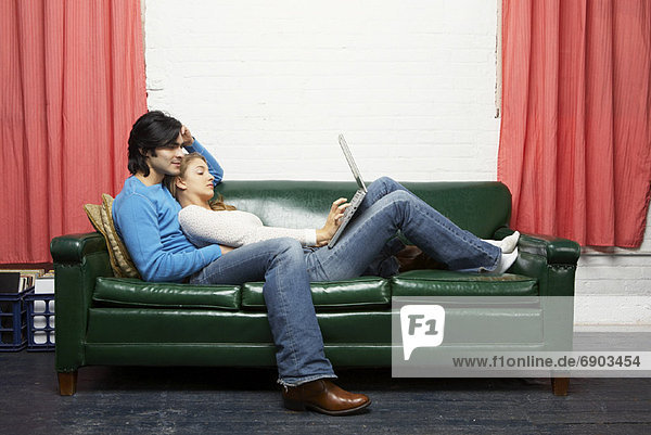 Couple Using Laptop on Sofa