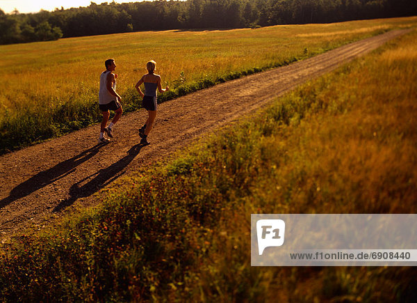 Couple Running on Dirt Road  Maine  USA
