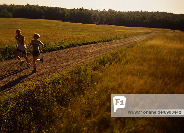 Couple Running on Dirt Road  Maine  USA