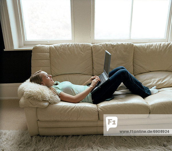 Teenage Girl Lying on Sofa Using Laptop Computer