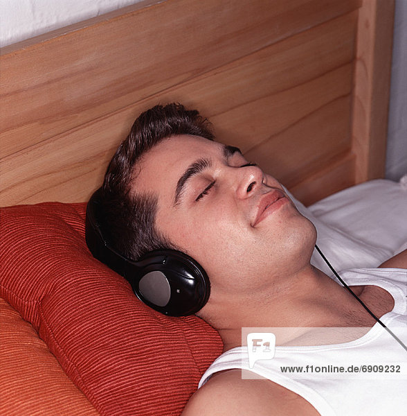 Man Lying on Bed  Using Headphones