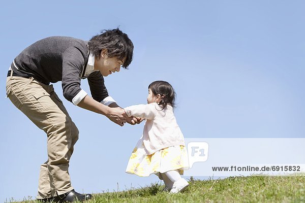 Young Father Holding Baby Girl's Hands