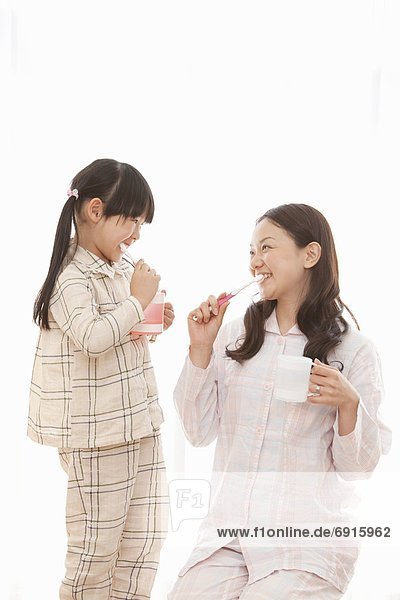 Young Woman and Daughter Brushing Teeth