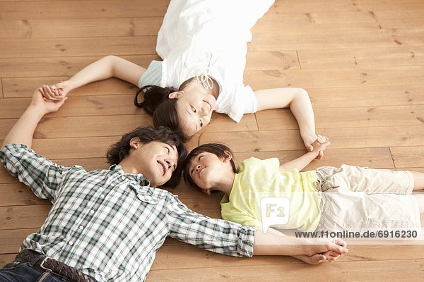 Family of Three Lying on Floor and Holding Hands
