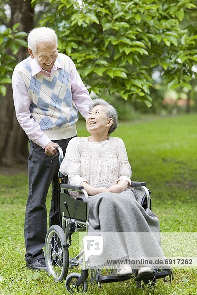Senior man pushing senior woman on wheelchair  Tokyo Prefecture  Honshu  Japan