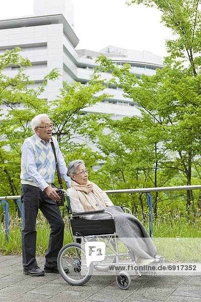 Senior man pushing senior woman on wheelchair  Kanagawa Prefecture  Honshu  Japan