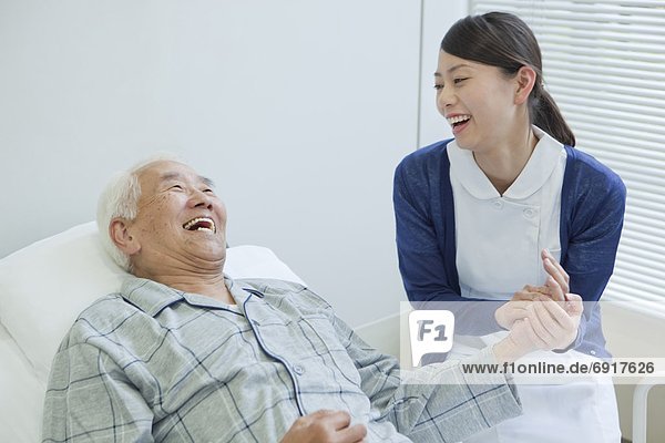 Senior man lying on bed talking to nurse  Kanagawa Prefecture  Honshu  Japan