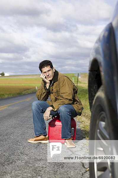 Man Sitting on Gas Can