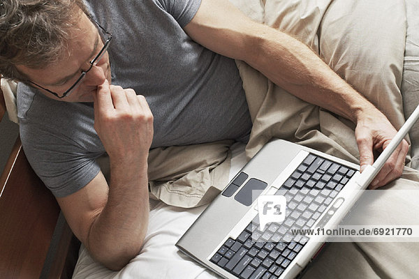 Man Using Laptop Computer in Bed