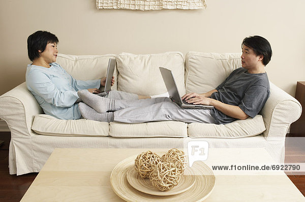 Couple Using Laptops on Sofa