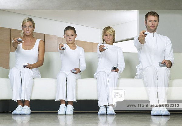Portrait of Family Sitting on Sofa  Using Remote Controls