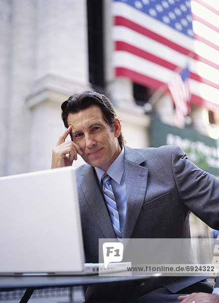 Businessman with Laptop Computer by American Flag