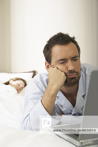 Man Using Laptop in Bed