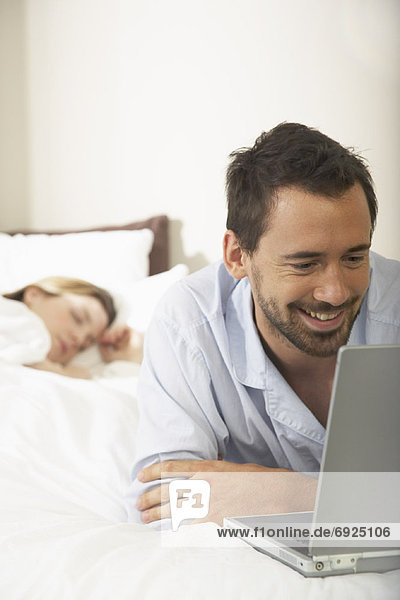 Couple in Bed  Man Using Laptop