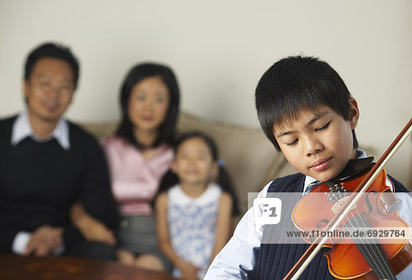 Portrait of Boy Playing Violin While Family Watches