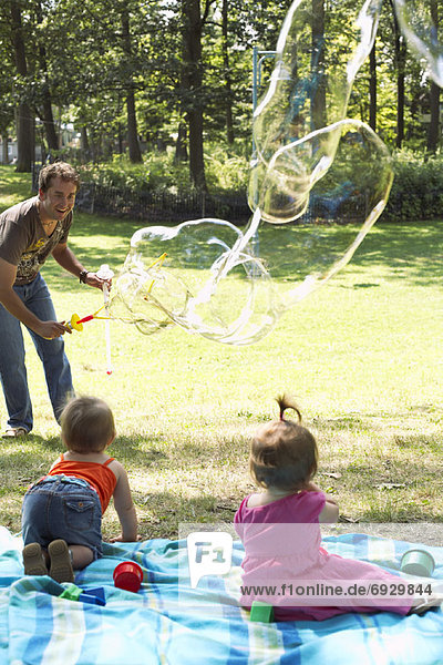 Father Blowing Bubbles while Babies Watch
