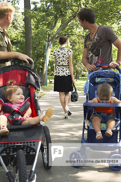 Men with Babies in Strollers Looking at Woman Walking Away