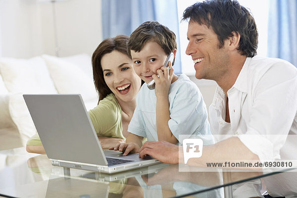 Young Family with Laptop Computer and Cellular Phone