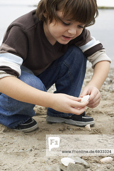 Boy Looking at Stone on Beach