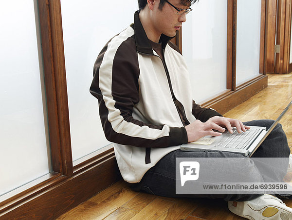 Man Sitting on Floor Using Laptop