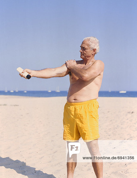 Man on Beach Applying Sunscreen