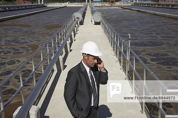 Businessman at Water Treatment Plant with Cellular Phone