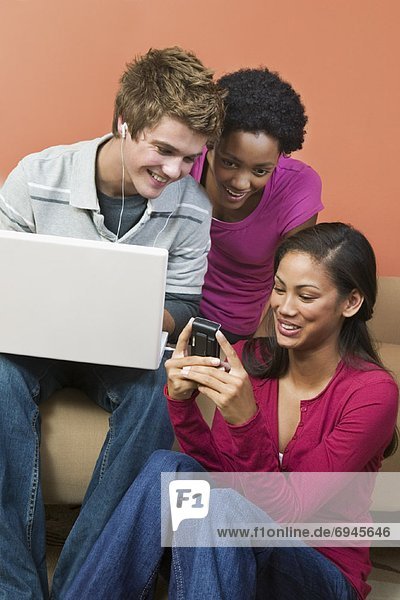 Group of Teens Using Laptop  and Cellular Phone