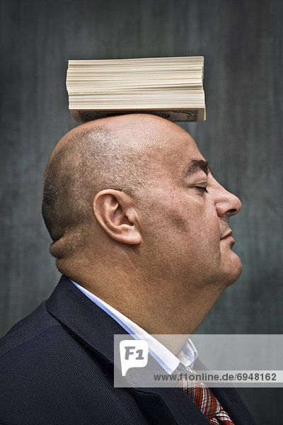 Businessman with Stack of Cash on Head