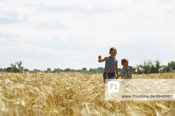 Brother and Sister Running through Grain Field