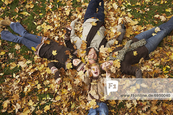 Portrait of Family Lying Down in Autumn Leaves