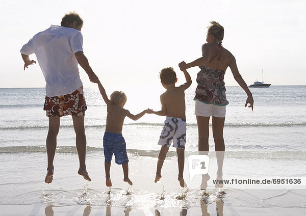 Family Jumping Together on Beach  Majorca  Spain