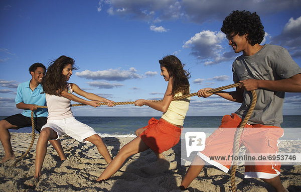 Friends Playing Tug-of-War on Beach
