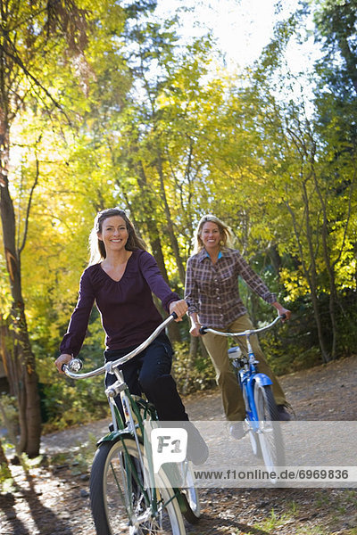 Two Women Riding Bicycles through Forest