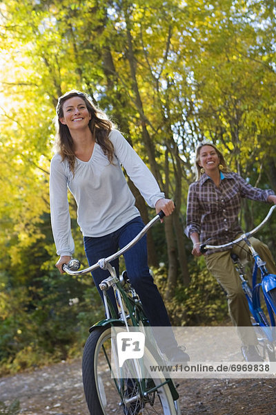 Two Women Riding Bicycles through Forest
