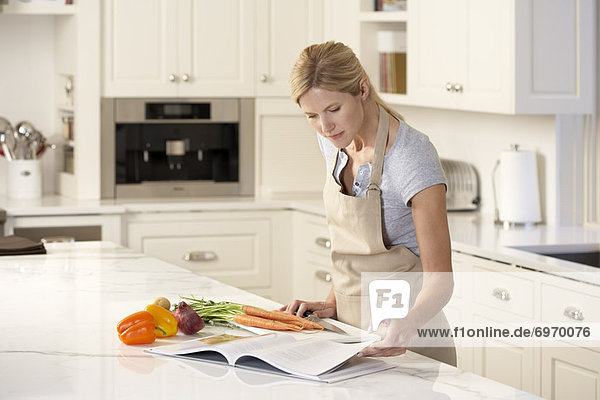 Woman Reading Cookbook in Kitchen
