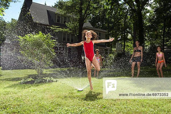 Family playing in backyard with sprinkler