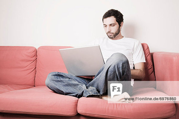 Young Man with Laptop on Sofa