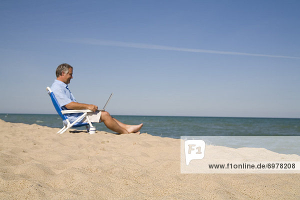 Man Sitting on the Beach Using Laptop Computer  Lake Michigan  USA