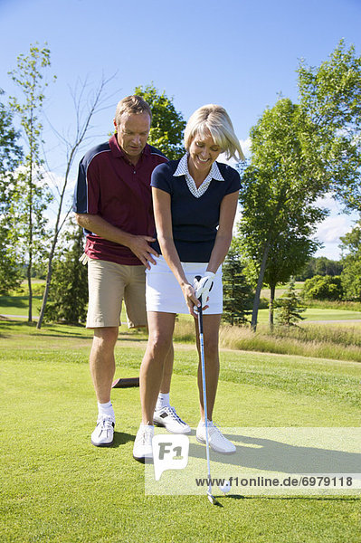 Man Helping Woman With Her Golf Swing