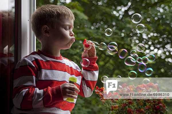 Kleiner Junge pustet Seifenblasen