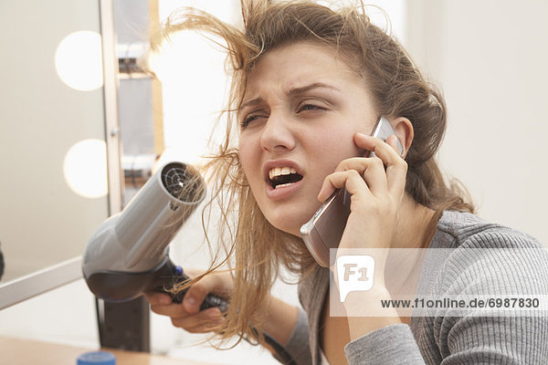 Teenager Using Hair Dryer and Talking on Cell Phone