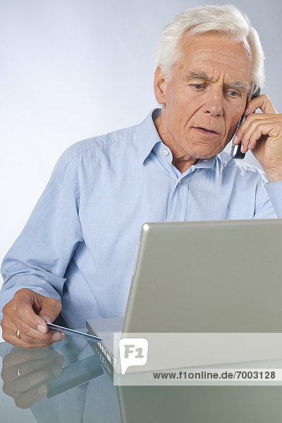 Man using Laptop and Cordless Phone