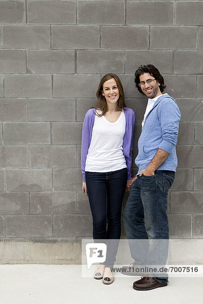 Portrait of Young Couple Standing in front of Stone Wall