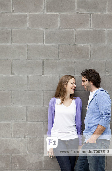 Young Couple Standing in front of Stone Wall