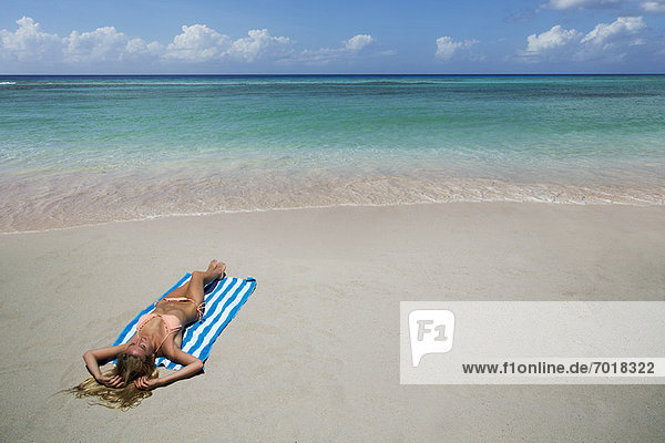 Frau auf Handtuch am Strand liegend