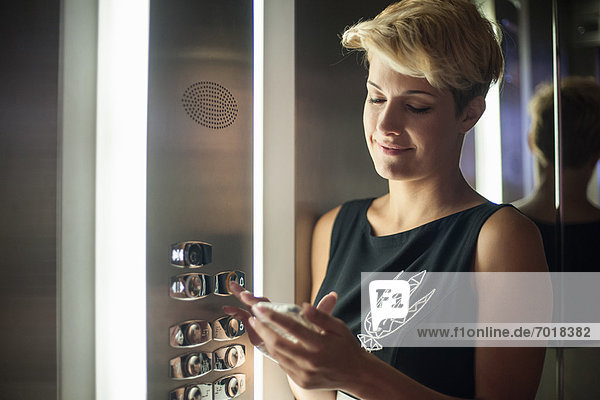 Frau mit Handy im Aufzug