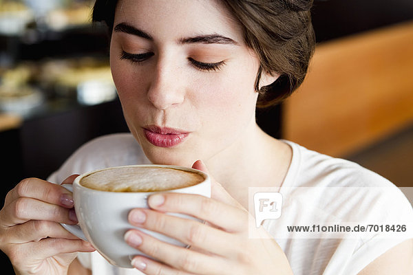 Frau bläst auf Kaffee im Cafe