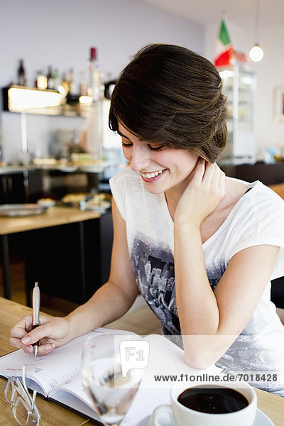 Smiling woman writing in cafe