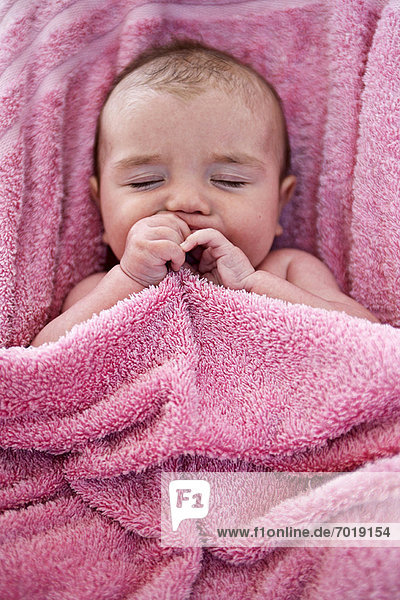 Close up of infant in pink towel