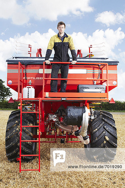 Farmer standing on tractor in field